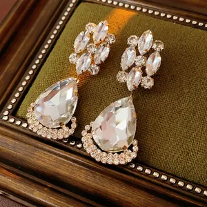 Vintage gold-plated drop earrings with rhombus crystals on a green velvet surface
