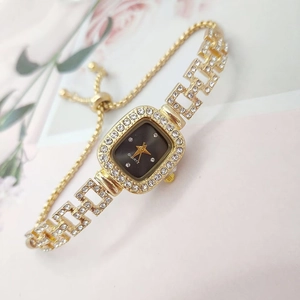 Detailed close-up of gold square watch with crystal accents and adjustable sliding buckle