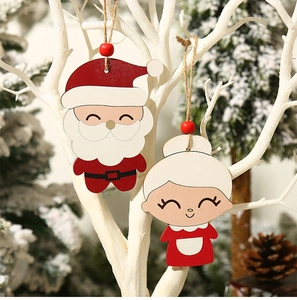 Detail view of cartoon Santa Claus and Mrs. Claus wooden hanging ornaments on a tree branch