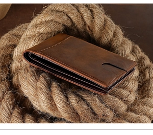 Vintage brown leather wallet for men on rustic rope roll with dark wood background