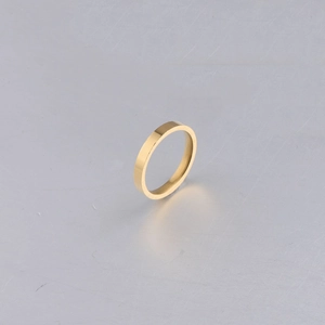 Macro shot of 3mm polished gold stainless steel minimalist band ring on metal surface