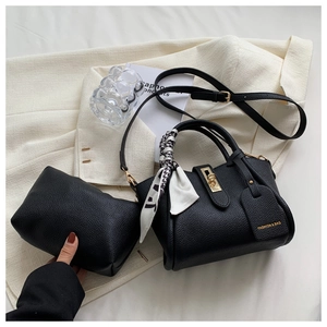 Détail d'un ensemble de sacs en cuir noir grainé avec fermoir doré et foulard
