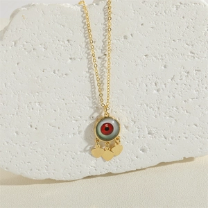 Evil eye necklace with red eyeball pendant and gold heart charms on stone background