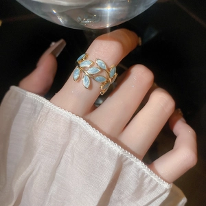 Makro-Detail des vergoldeten Blatt-Rings mit funkelnd hellblauer Emaille-Füllung