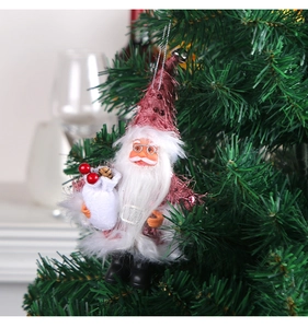 Detail of pink sequin Santa ornament hanging on green pine branch with gift bag