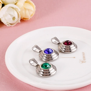 Stainless steel pendants with red, blue, and green zircons on a white plate with flowers