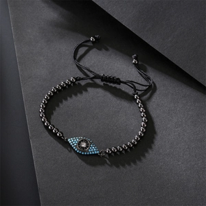 Detailed close-up of beaded evil eye bracelet with cubic zirconia on black braided cord