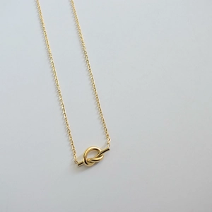 Macro detail of gold knot pendant and delicate link chain made of titanium steel