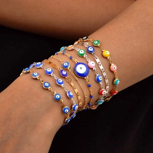 Pulseras de acero inoxidable con ojo turco y colgantes de esmalte de colores puestas en la muñeca