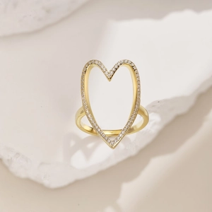Macro shot of gold hollow heart ring with sparkling paved zircon stones on white stone