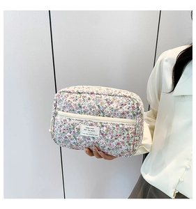 Close-up of floral quilted cotton makeup bag with white label held by a model