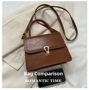 Detail of vintage brown leather handbag with gold metal clasp on white blazer fabric