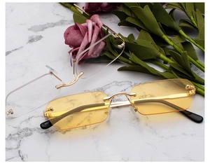 Diamond-cut rimless square sunglasses with yellow and clear lenses on marble background