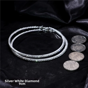 Macro view of 9cm silver hoop earrings with white crystals and coin size reference