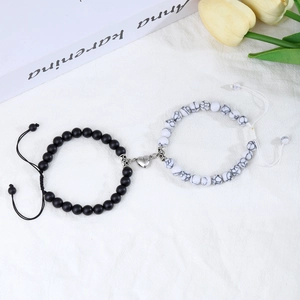 Detail view of heart-shaped magnetic clasp on black and white beaded couple bracelets