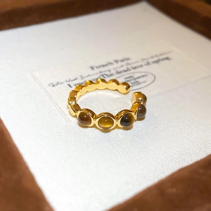 Détail d'une bague plaquée or avec cinq pierres œil de tigre rondes sur un anneau perlé