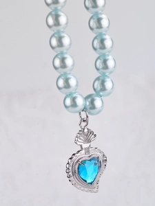 Macro detail of blue heart gemstone pendant with light blue pearls on a hip hop necklace