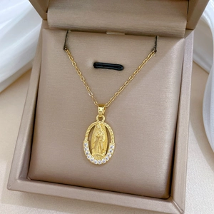 Detailed macro view of a gold oval Virgin Mary pendant with sparkling diamond halo inlay