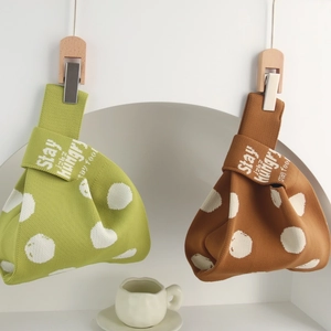 Close-up of knit wrist bags in green and brown with white polka dots and Stay Hungry text