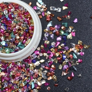 Iridescent irregular metal nail foils in vibrant colors shown in a white round container