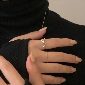Detailed close-up of S925 sterling silver bow ring and minimalist band on model's hand