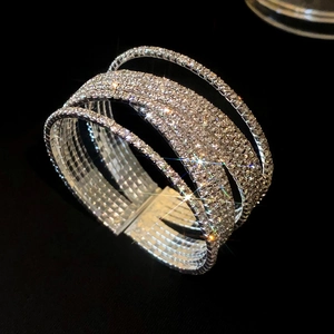 Detailopname van een brede zilveren meerlaagse kruisarmband met fonkelende steentjes
