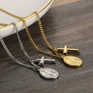 Gold and silver stainless steel oval medal and cross pendant necklaces on wood