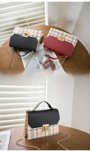 Detail of vintage plaid crossbody bag with gold metal clasp and chain strap on wooden table