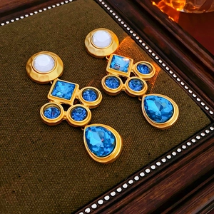 Macro view of vintage gold earrings with blue crystals on dark green velvet base