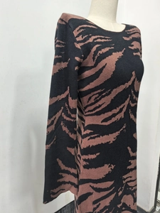 Detail of round neck knitted long dress featuring brown tiger print pattern on black fabric