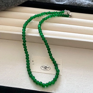 Detail of green beaded pearl necklace with silver clasp on white jewelry tray