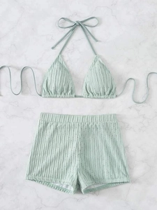 Detail of light green ribbed bikini fabric featuring delicate eyelet texture and ruffles