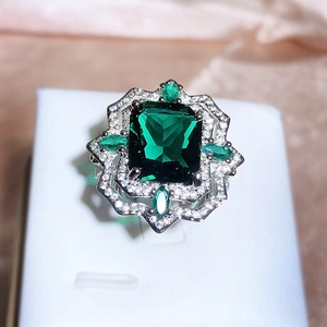 Detailed view of luxury square green gemstone ring with diamonds on pink silk