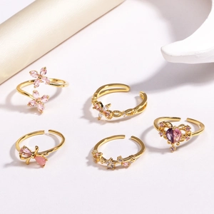 Vue détaillée de cinq bagues dorées avec motifs de papillons, fleurs et zircons roses