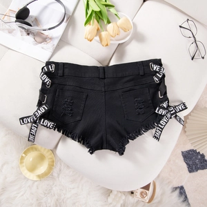 Dettaglio di pantaloncini di jeans neri strappati con nastro Love e texture usurate