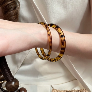 Close-up of a pair of amber leopard print acrylic resin bangles on a woman's wrist
