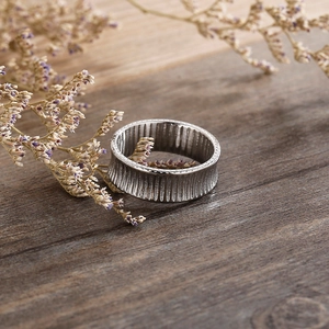 Macro shot of striped silver stainless steel ring with textured details on wood background