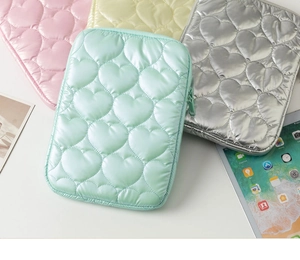 Detailed view of heart-quilted macaron laptop sleeves in pink, mint, yellow and silver