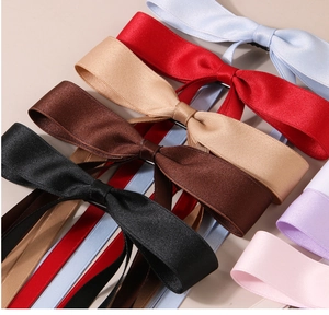 Close-up of assorted colorful satin ribbon bow hair clips showing silky fabric texture