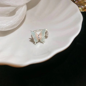 Macro shot of gradient enamel butterfly ring with zirconia stones on a shell