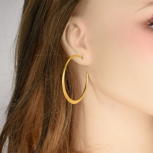 Close-up of model wearing large golden vintage spiral hoop earrings in stainless steel