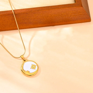 Détail du collier avec pendentif soleil et lune doré sur un support en bois