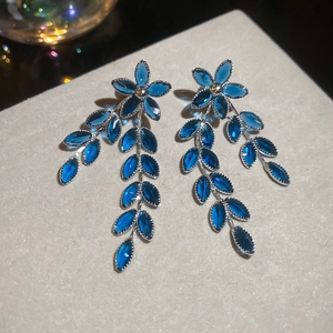 Makroaufnahme von Kristall-Blumenohrringen mit blauen Edelsteinen und silbernen Details