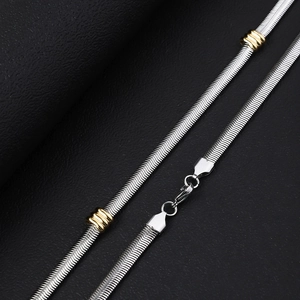 Flat 6mm stainless steel snake chain necklace with gold beads on black leather background