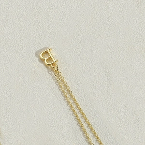 Macro shot of gold letter B pendant on a delicate chain with a polished metallic finish