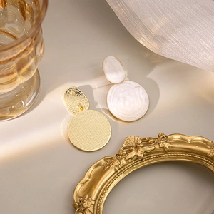 Elegant gold geometric earrings with white marble resin pendants in a lifestyle setting