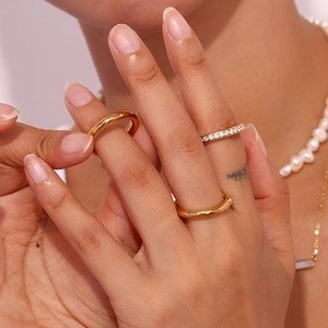 Detail of three 18K gold plated rings and pearl necklace worn by a fashion model