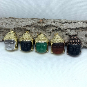 Detailed view of five colored Buddha head pendants arranged on natural wood bark texture