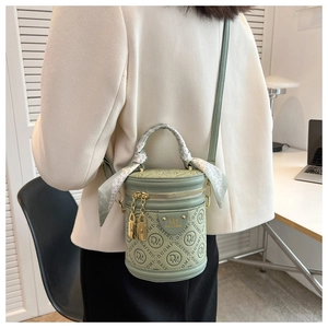 Detail of green cylinder bucket bag with embossed monogram and silk scarf handle