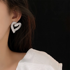 Close-up of a silver hollow heart earring with sparkling zircons worn on a model's ear